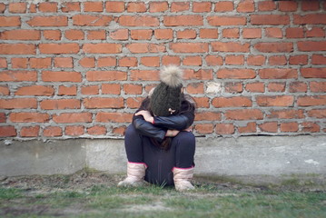Fototapeta na wymiar A Sad and lonely girl beside brick wall