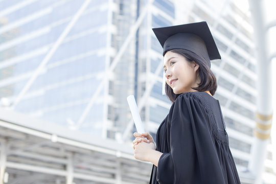 Young Asian Woman Students wearing Graduation hat and gown at University, Woman Students  with Graduation Concept.