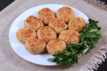 Fried cutlets on a white plate on a table on a gray background.