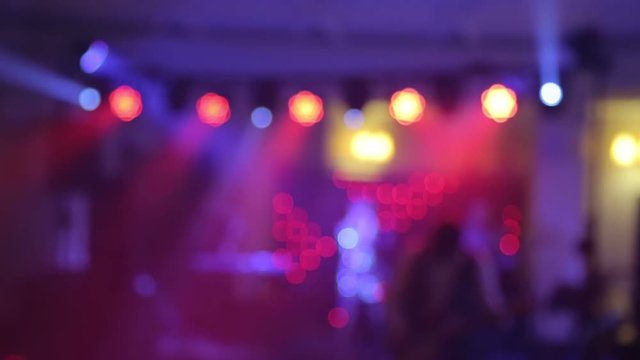 Background of the dance is blurred people dancing in a nightclub. Blue and purple colors