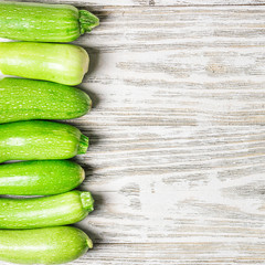 Fresh zucchini on white shabby wooden background. Top view, space for text.