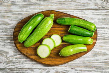 Summer vegetables zucchini and squash sliced on cutting board on wooden background. Top view, space for text. 