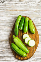 Summer vegetables zucchini and squash sliced on cutting board on wooden background. Top view, space for text. 