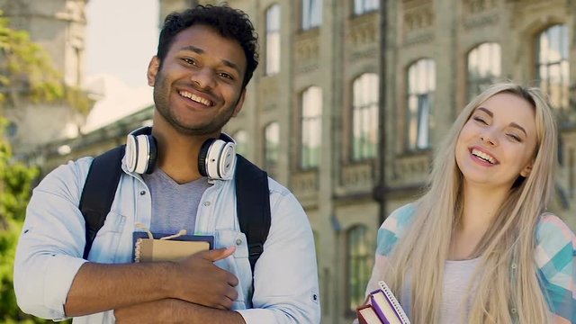 Female and male students smiling at camera, showing thumbs-up, quality education