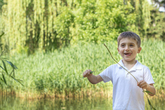  Happy little boy playing at the pond in the city park on a summer sunny day. Close up. Beautiful summer background with copy space