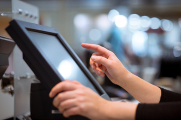 Young woman hand doing process payment on a touchscreen cash register, finance concept (color toned image) - obrazy, fototapety, plakaty