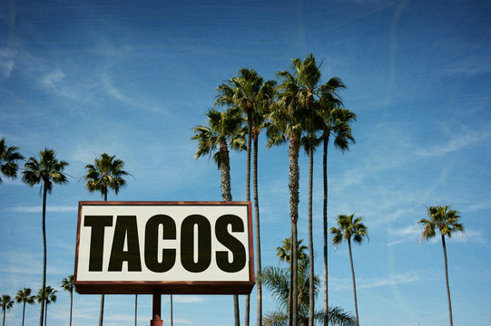 aged and worn tacos sign with palm trees