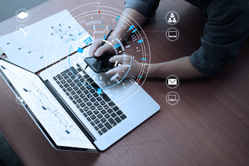 close up of businessman working with smart phone and digital tablet and laptop computer  on wooden desk in modern office with virtual icon diagram