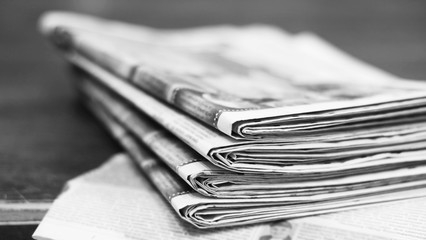 Fresh morning newspapers on the table. Bunch of daily journals with news folded and stacked in the pile. Blurred background texture