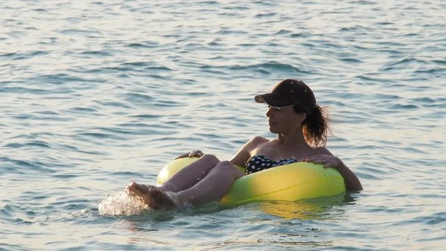A happy girl is floating in the sea on an inflatable lap.