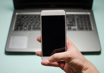 Man holds a white mobile phone on a laptop background