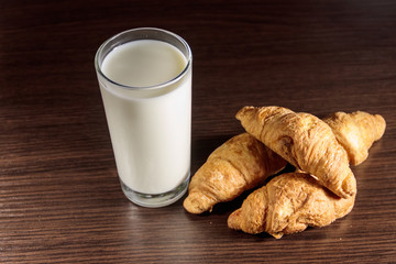Glass of milk and fresh croissants on wooden table