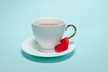 Two white cups and a red heart on Valentine's Day stand on a turquoise background. Valentine's day card