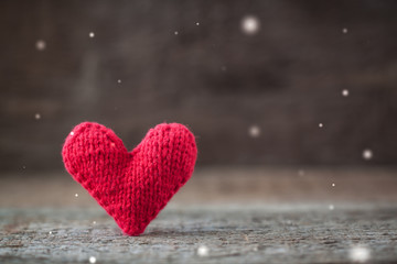 Handmade red knitted Valentine heart on rustic wooden background with fairies effect and copy space.