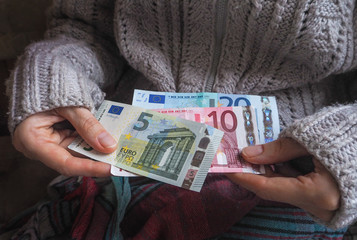 Lady in a knitted sweater takes out Euro banknotes from the sleeve. The money in the sleeve.