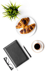 Light breakfast of businessman. Coffee and croissant near notebook and glasses on white background top view