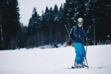 Female skier on a slope in the mountains. Frozen dark forest in the background. Skier in winter forest mountains skiing downhill