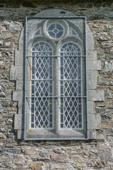 Metal mesh screen over a stained glass window of a church