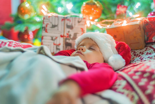 Cute little baby girl sleeping near Christmas tree