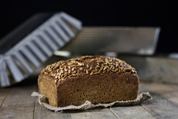 Fresh and crusty bread with sunflower on a wooden table. Bread and baking plate in the bakery.