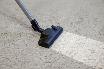 Cleaning the carpet using a vacuum cleaner.