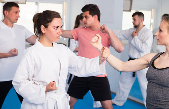 Women with men are practicing new karate moves in pairs