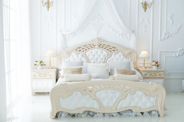 Bed in a large beautiful bedroom in the style of rococo.