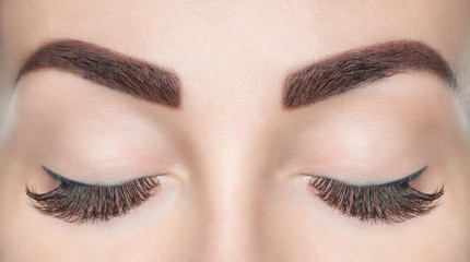 Eyelash extension procedure. Beautiful Woman with long lashes in a beauty salon.