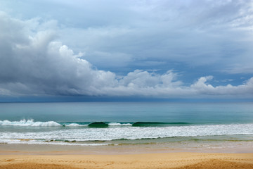The coastline of the sandy beach, high waves and white clouds