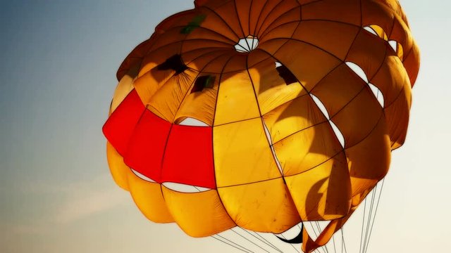 Parachute dome for parasail against the sky. It is illuminated by the rays of the setting sun. Water sports on the beach.