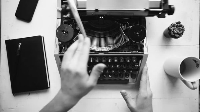 Writer typing with retro writing machine. View from above.