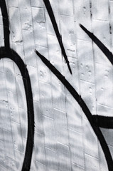 A fragment of a graffiti pattern, applied to a wall of cold tiles, which is covered with a fine condensate. The concept of street art in inappropriate weather