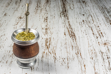 Traditional Argentinian yerba mate tea in a calabash gourd with bombilla stick against wooden...