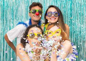 Partygoers are celebrating Carnival in Brazil. Girls blow the confetti from the palm of their hand..