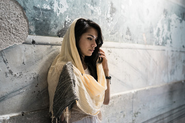 Portrait of a thoughtful sad girl in a headscarf on the head of the light sitting in the temple,...