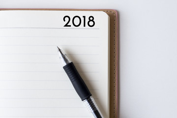 Conceptual,notebook on a white table. open diary and pen with 2018 words