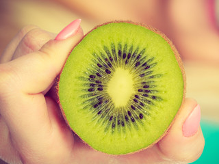 Woman holding green kiwi fruit