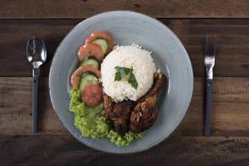 Popular Malaysian dish Nasi Ayam or chicken rice with baked chicken pieces, tomato, cucumber and salad.