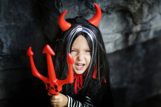 portrait of cute little girl in devil costume for halloween