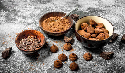 Chocolate truffles, cocoa powder and grated chocolate in bowls.
