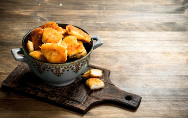 Chicken nuggets in a bowl on the board.
