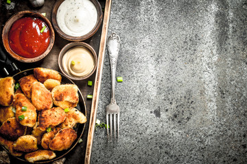 Chicken nuggets with different sauces on an old tray.