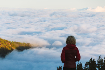 Young woman  above cloud inversion in desert landscape while sunrise