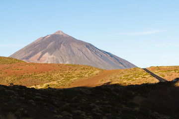 Road with sunrise light on volcanic hills in desert landscape