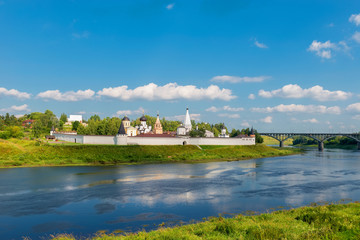 Obraz premium View on ancient white-stone Convent of the Dormition built in 16 century on Volga River bank with reflection in water. Staritsa, Tverskoy region, Russia.