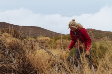 Fototapeta na wymiar Young girl in jacket hiking in grassland landscape
