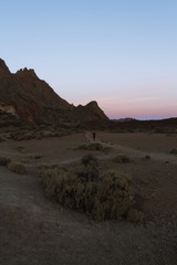 Woman walking in  desert landscape at dawn with colorful skies
