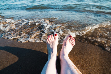 Female feet and sea wave on a summer