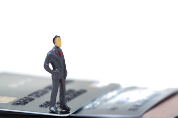 Figure miniature businessman or small people standing with stack of credit card on white background for money and shopping concept.