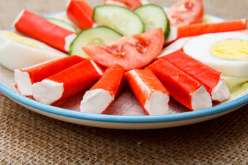 Crab sticks, boiled egg and freshly sliced tomato and cucumber on plate